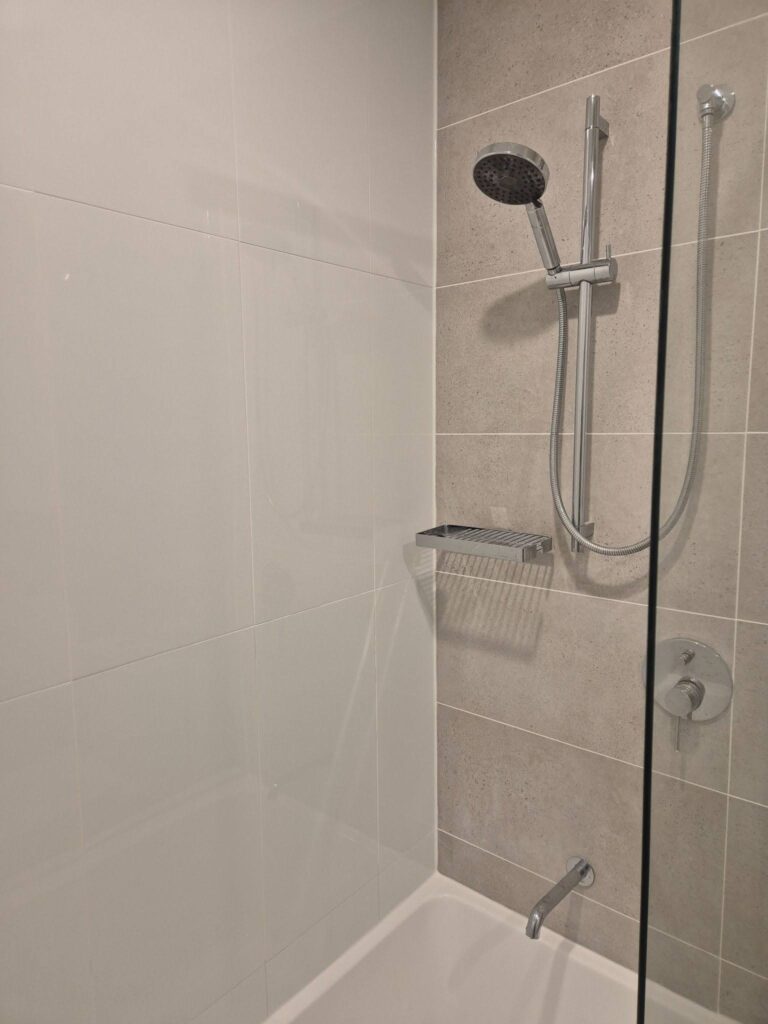 white shower tiles and black mosaic niche with fresh grout lines.